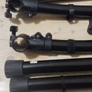 Šest černých kovových trubek, pravděpodobně částí stativů. Některé mají na koncích plastové patky a některé jsou vybaveny svěrkacími mechanismy s úhl…