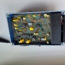 Fotografie zachycuje vnitřek efektového pedálu v modrém kovovém šasi. Na základní desce jsou osazeny různé elektronické součástky, včetně integrovaný…