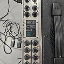 Kytarový zesilovač v černé koženkové skříně s rukojetí. Na kovovém předním panelu je nápis VINTAGER AC112 a tabulka s technickými specifikacemi. Zaří…