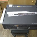 Fotografie znázorňuje uzavřenou krabici s USB audio rozhraním. Na černé krabici je zobrazen produkt v rackovém provedení s bílým předním panelem a ná…