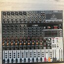 Černý mixovací pult značky behringer, model XENYX X1832USB. Zařízení obsahuje více vstupních kanálů s potenciometry, posuvníky a digitální displej v…