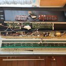 Fotografie zachicuje otevřený elektronický hudební nástroj s vyloženým horním krytem. Uvnitř jsou vidět různé elektronické desky, kabeláž a dva ovlád…
