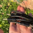 Černý kabel s dvěma konektory typu jack. Na kabelu je bílý nápis Professional Low-noise Guitar Cable a červené logo RONNEX. Povrch konektorů je černý…