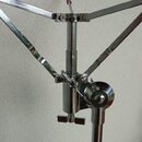 Detail chromovaného kovového stojanu s mechanismem pro uchycení nástroje. Jsou vidět dvě rozkládací ramena s početnými šrouby a dvěma utahovacími kno…