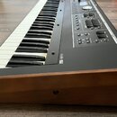 Černý klavír s dřevěnou lištou v přední části. Na černé ploše je viditelné logo „Roland“. Ovládací panel obsahuje několik posuvníků, tlačítek a malý…