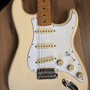 Krémová elektrická kytara s bílým pickguardem a hnědým javorovým hmatníkem. Nástroj má tři snímače typu single-coil, jeden přepínač a tři otočné pote…