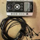 Stříbrný elektronický modul s černým ovládacím panelem. Na přístroji jsou nápisy Roland, PERCUSSION SOUND MODULE TD-9 a logo V-Progs. K modulu je při…