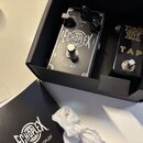 V černé krabici jsou dva kytarové efekty. První je stříbrný pedal s nápisy ECHOPLEX a DELAY, vybavený dvěma knoflíky označenými GAIN a VOLUME. Vedle…