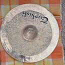 Kruhový činel stříbrné barvy s viditelnou kovanou strukturou povrchu. Na povrchu je černý nápis „Turkish“ a menší text „Handmade cymbal from Turkey“.…