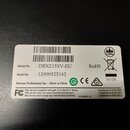 Fotografie zachycuje bílou papírovou nálepku s technickými údaji nalepenou na černém povrchu. Na štítku je uveden Model No.: DBX215SV-EU a Serial No.…