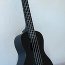 Černý ukulele s matným povrchem. Na hlavě nástroje je bílý nápis „The Waterman“. Nástroj vykazuje čistý povrch bez viditelného opotřebení.