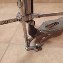 Detailní pohled na kovový mechanismus bicího pedálu. Povrch vykazuje známky opotřebení, oxidaci a místní znečištění. Na fotce nejsou žádné čitelné zn…