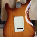 Zadní strana elektrické kytary s lakovaným povrchem v hnědém odstínu sunburst. Na kovém krytu krkovnice je vyryto logo "Fender" a nápis "MEXICO CALIF…