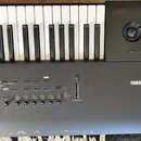 Černý klávesový nástroj se značkou KORG na pravé straně. Panel obsahuje řadu tlačítek s nápisy jako TRANSPOSE, OCTAVE, AUDIO IN, DRUM, ARP a LATCH, d…