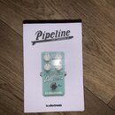 Bílá krabice s nápisem Pipeline TAP TREMOLO a logem tc electronic. Uvnitř je zobrazen zelený kytarový pedál s nápisy SPEED, DEPTH a VOLUME u ovládací…