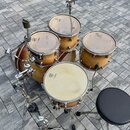 Celá bicí souprava v přírodním dřevěném provedení s kovovým hardwarem. Na blanách jsou viditelné loga REMO. Souprava obsahuje basový buben, dva tom-t…