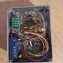 Šedý plastový kryt s vnitřním zapojením elektroniky a barevným kabelážním svazkem. Na zelené desce je nápis 2018.10.20 a na hnědé desce je čitelný ná…