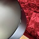 Detailní pohled na hranu černého hudebního nástroje s matným povrchem. Na hraně jsou vidět několik odřapů a odloupané vrstvy laku. Žádné značky ani n…