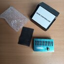 Na fotografii je modrý přístroj s nápisem BAND CONTROLLER, který má řadu posuvníků a jeden otočný knoflík. Součástí je černá krabice s bílým nápisem…