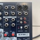 Detailní záběr na ovládací panel míchacího pultu značky Soundcraft, model EPM 6. Jsou vidět různé typy konektorů (XLR, jack), přepínače a regulační k…
