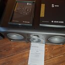 Černý studiový monitor s dvěma basovými reproduktory a jedním středněvelkým reproduktorem uprostřed, na kterém je nápis ADAM. Na horní části přístroj…