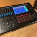 Černý ovládací pult s modrými detaily a nápisy. Na zařízení jsou viditelná loga SAGITTER a QUIVER, nápisy CONTROLLERS a PLAYBACKS. Pult obsahuje bare…