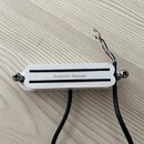 Bílý humbucker s černým krytem snímače. Na krytu je uveden nápis Seymour Duncan. Z nástroje vedou černé kabely s odhalenými barevnými vodiči v koncíc…
