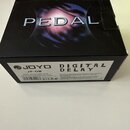 Fotografie znázorňuje kartonovou krabici od efekt pedálu. Na horní části je velký nápis PEDAL, na spodní straně jsou loga a texty JOYO, JF-08 a DIGIT…