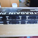 Dvě černé rackové jednotky s nápisy ULTRAGAIN PRO, MODEL MIC2200 a logem behringer. Na zadních panelech jsou vidět vstupy a výstupy s popisky INPUTS,…