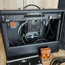 Kytarový kombozesilovač s černým koženým potahem, u kterého je otevřený zadní panel. Na horní liště je nápis MESA/BOOGIE a uvnitř na reproduktoru jso…