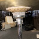 Detailní záběr na spodní stranu činchu hi-hat umístěného na chromovaném stojanu. Na spodní straně činchu je vidět světlá, znečištěná plstěná podložka…