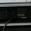 Zadní strana černého zesilovače umístěného v transportním kufru. Na zařízení jsou nápisy TYPE: WARWICK PRO FET 50, WARWICK AMPLIFICATION (CHINA) a SE…