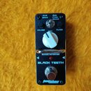 Černý kytarový efekt s nápisem BLACK TEETH a VINTAGE DISTORTION. Na horní straně jsou dva černé otočné knoflíky s popisky VOLUME a FILTER, jeden bílý…