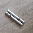 Dvě stříbrné kondenzátorové mikrofony v tubusovém tvaru položené na dřevěné podlaze. Na těle mikrofonů je viditelné logo s nápisem AKG a modelové ozn…