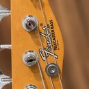 Detail hlavy basové kytary z přírodního dřeva. Na povrchu je černé logo Fender s nápisem TELECASTER BASS a PAT 2.968.204. Jsou vidět čtyři chromované…