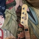 Hlava basové kytary v krémové barvě s nápisem Fender TELECASTER BASS. Na hlavě jsou čtyři chromované ladičky. Hřifo je vyroben ze světlého dřeva s tm…