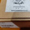 Kartonová krabice s bílým štítkem na horní straně. Na štítku je černobílý obrázek postavy, nápis PARVATI a webová adresa WWW.DEMONPEDALS.COM. Na bočn…