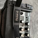 Černý kompaktní kytarový kombozesilovač s plastovým krytem. Na předním panelu jsou nápisy MICRO CUBE, INPUT, ACOUSTIC, JC CLEAN, BLACK AMP, CRUNCH, C…