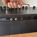 Černý kytarový kombozesilovač s kovovou rukojetí. Na zadním panelu je nápis YAMAHA THR30II Wireless a označení konektorů LINE OUT (L, R), USB a 15V.…