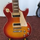 Elektrická kytara s trupem v červeno-žlutém sunburst provedení a krčkem z tmavého dřeva. Nástroj má dva humbuckery v krémových rámečcích, krémový pic…