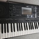 Černý digitální klavír s bílými a černými klávesami. Na horním panelu je nápis YAMAHA a označení modelu PSR-SX900. Nástroj obsahuje displej, množství…