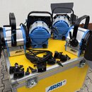 Na žlutém transportním kufru s nápisem ARRI stojí čtyři modré studiové reflektory. Dva krajní kusy mají černé klapky a nápisy T1 a ARRI. Dva prostřed…