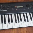 Černý klavírní syntetizátor s bílými a černými klávesami. Na levé straně je nápis YAMAHA a na pravém okraku svisle napsáno 64xw. V horní části panelu…