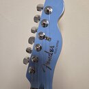 Modrá hlava elektrické kytary s chromovanými ladičkami. Na povrchu je černý nápis Fender a vedle něj svisle napsaný text TELECASTER. Nástroj vykazuje…