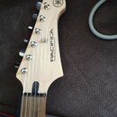 Hlava elektrické kytary z přírodního světlého dřeva. Je na ní viditelné logo YAMAHA v kruhu a nápisy PACIFICA oraz Yamaha Guitar Development. Povrch…
