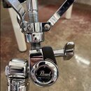 Detail chromovaného mechanismu stojanu s černým plastovým knoflíkem. Na kulatém kovovém krytu je bílý nápis Pearl a pod ním text GYRO-LOCK SYSTEM. Po…