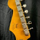 Zadní strana hlavy kytary z vybarveného dřeva s chromovanými ladicími kolíky. Na dřevě je černý nápis „Designed and Blocked by Fender®“, „Crafted in…