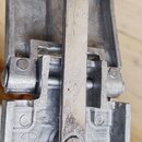 Detailní pohled na kovový mechanismus pedálu v stříbrné barvě. Na spodní části je vyraženo logo <T> a nápis TAY-E®, vedle toho je vidět text IN TAIWA…