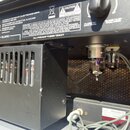 Černý kytarový zesilovač značky Peavey s nápisem ValveKing VK102. Na zadním panelu jsou viditelné varovné nápisy v angličtině a francouzštině, označe…