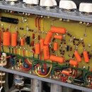 Fotografie zachycuje vnitřek kytarového zesilovače s viditelným zapojením komponentů na žlutém podkladu. Jsou zde vidět elektronické součástky, zejmé…